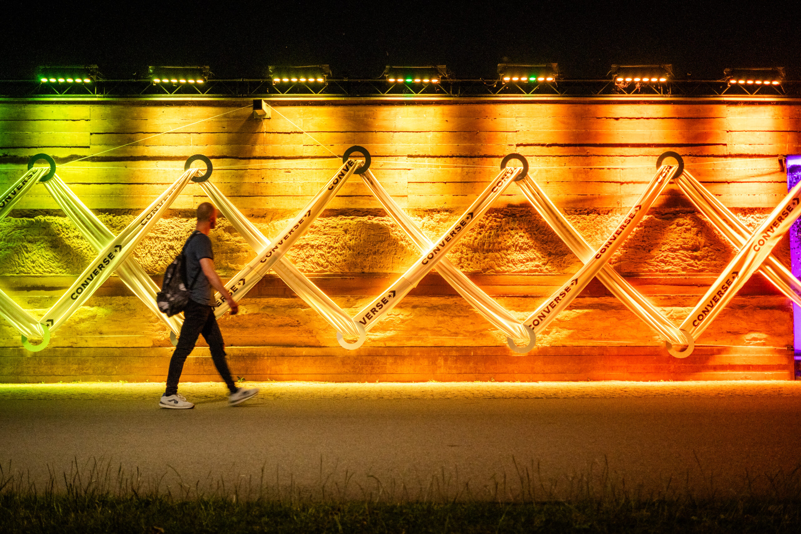 Osoba idąca w nocy obok kolorowej reklamy