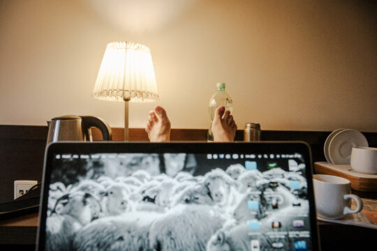 Copyright: Agnieszka Budzyńska Nogi na stole, na których leży otwarty komputer