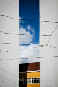 Copyright: Agnieszka Budzyńska Żółty dom pomiędzy dwoma słupami mostu w Lizbonie