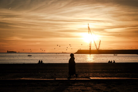 Copyright: Agnieszka Budzyńska osoba idąca po plaży w Porto o zachodzie słońca
