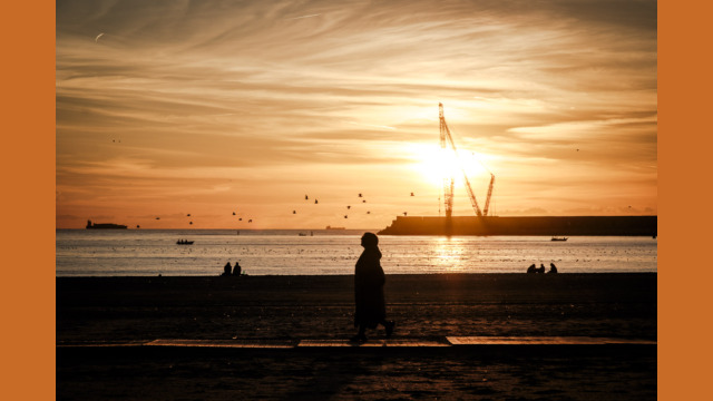 Copyright: Agnieszka Budzyńska osoba idąca po plaży w Porto o zachodzie słońca