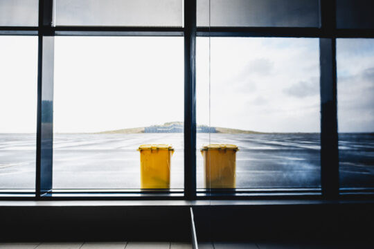 Copyright: Agnieszka Budzyńska Odbity żółty śmietnik w szybie na lotnisku na Pico