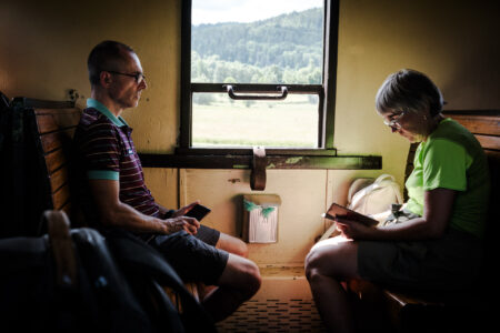 Dwie osoby siedzące w zabytkowym pociągu.