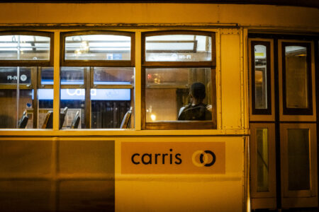 Żółty tramwaj z jedną osobą siedzącą tyłem