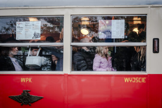 Zatłoczony zabytkowy czerwony tramwaj widziany z boku