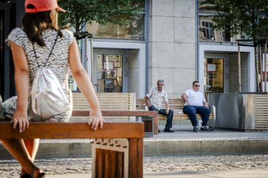 Dziewczynka siedząca na przystanku i dwaj panowie