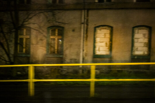 Dom z zamurowanymi oknami i żółta barierka