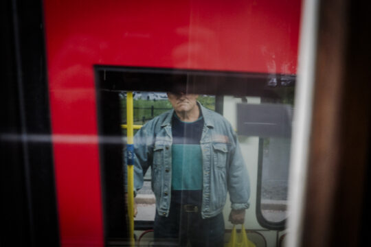 Osoba stojąca przed tramwajem w reklamówka w dłoni