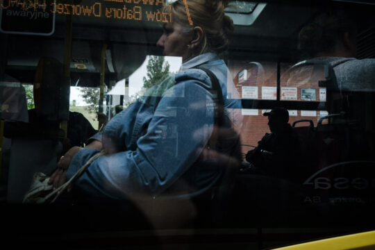 Ludzie w autobusie widziani z okna tramwaju