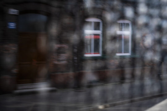 Okna kamienicy rozmazane przez szybę