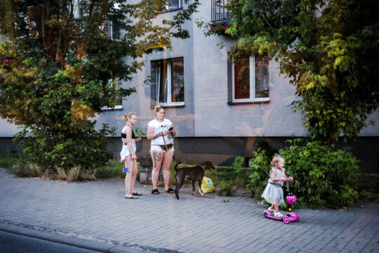 2 kobiety, pies i dziecko na rowerku na przystanku