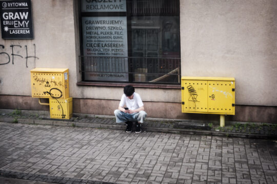 Osoba kucająca na przystanku